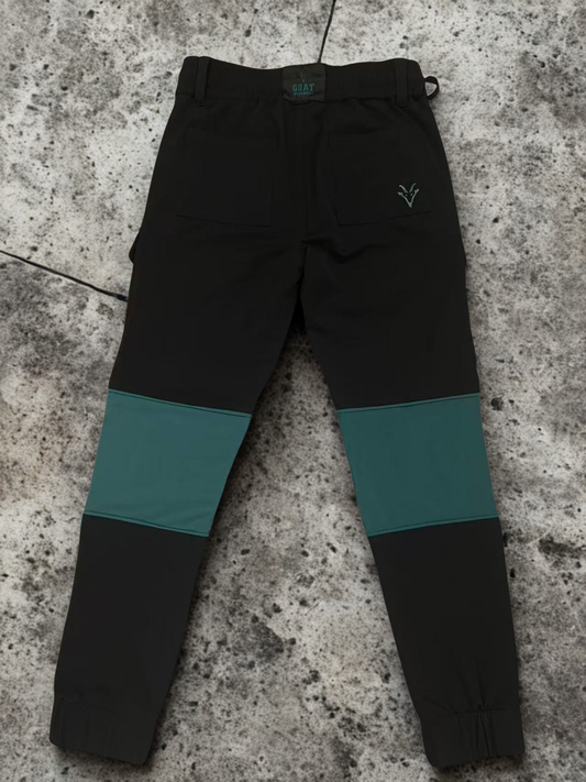 Black construction workwear trousers  with teal accents on a textured surface