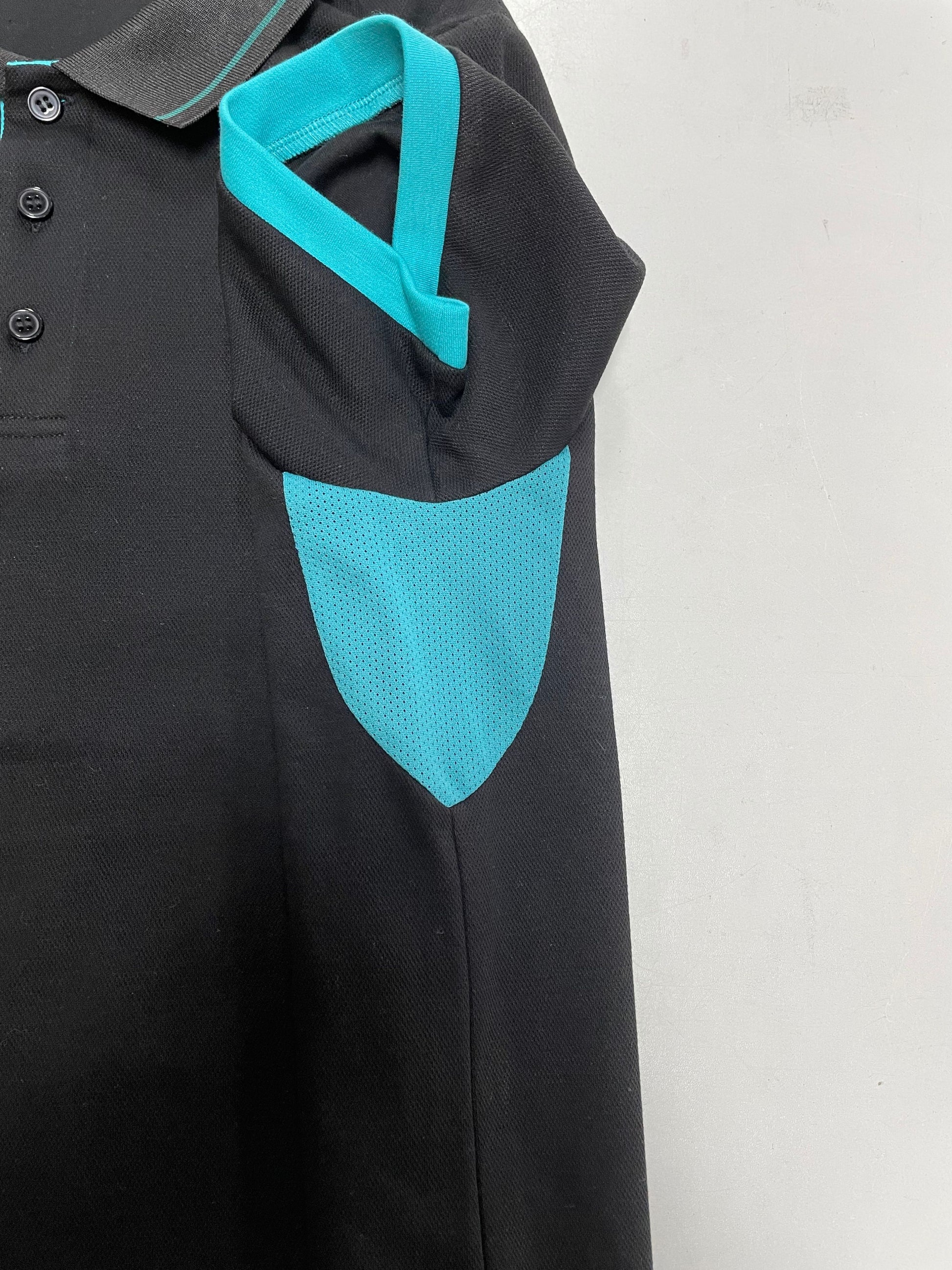 Detail of black polo shirt with teal accents on a white background