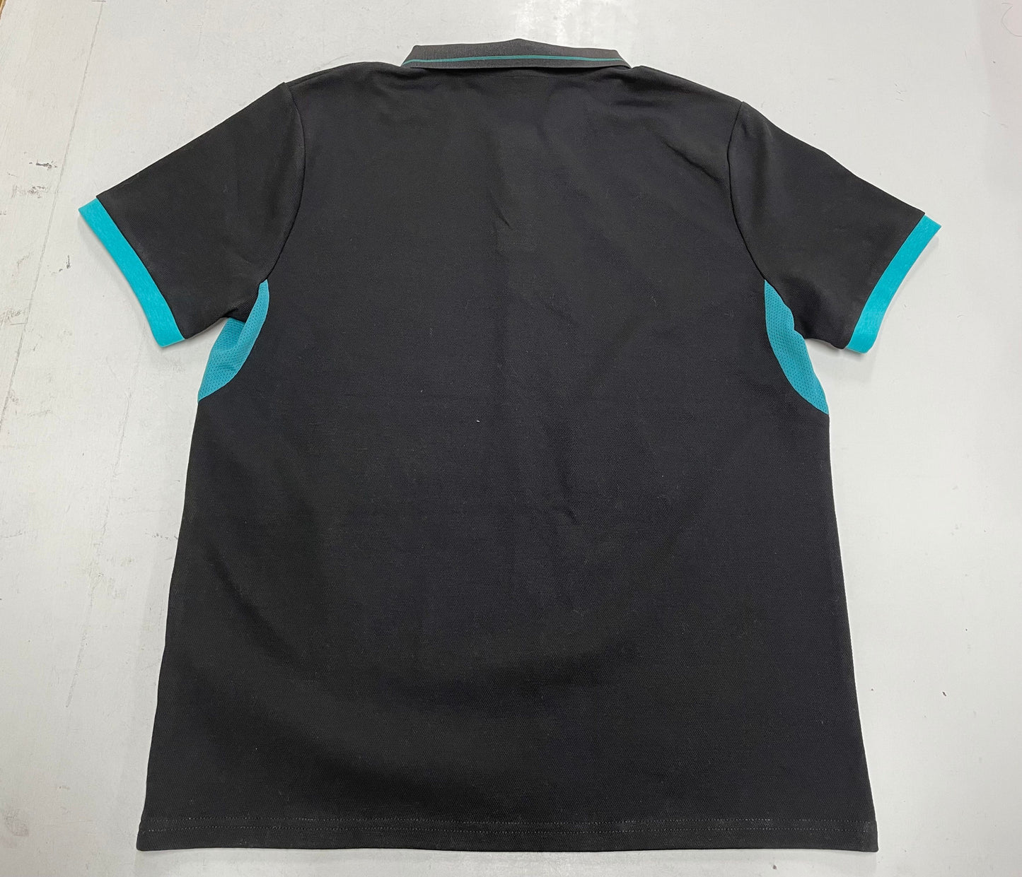Black polo shirt with blue accents on a white background